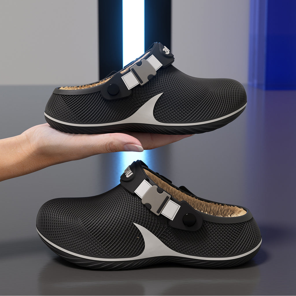 Two black plastic slippers with tan fleece lining and buckle straps, held by a hand against a blue and grey background.