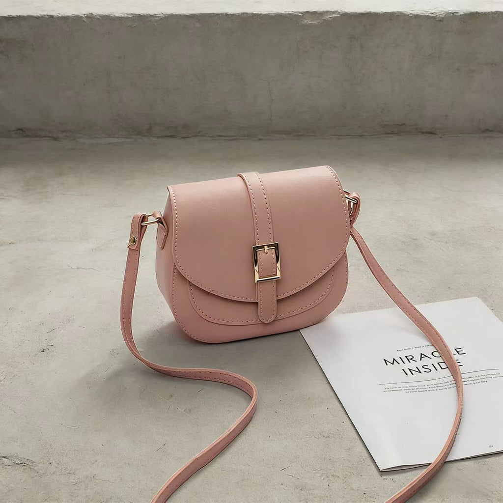 Simple metal-buckle flap crossbody saddle bag with an adjustable shoulder strap.
