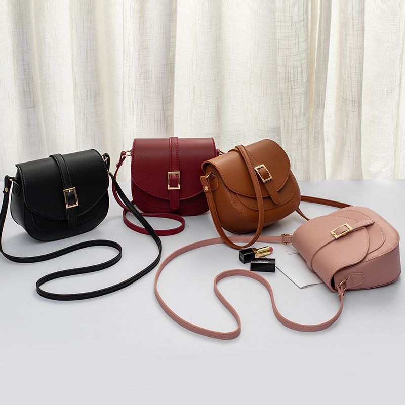 Simple metal-buckle flap crossbody saddle bag with an adjustable shoulder strap.